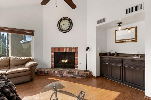 living room featuring high vaulted ceiling, sink, ceiling fan, dark hardwood / wood-style floors, and a fireplace