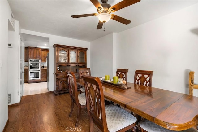 dining area with ceiling fan and dark wood-type flooring