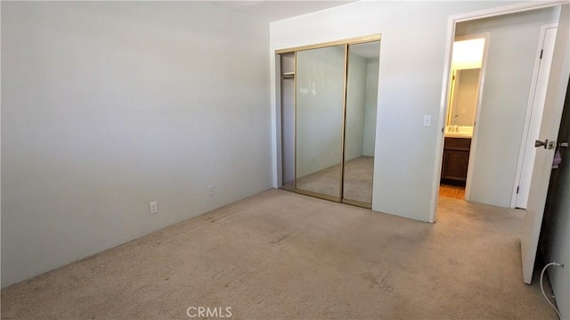 unfurnished bedroom featuring light carpet and a closet