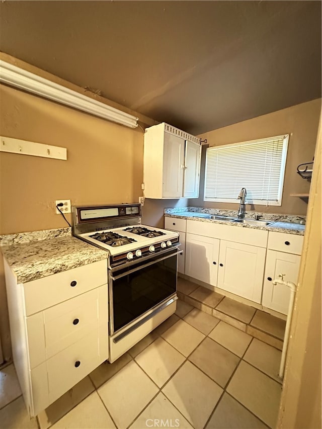 kitchen featuring light tile patterned flooring, white range with gas cooktop, white cabinetry, and sink