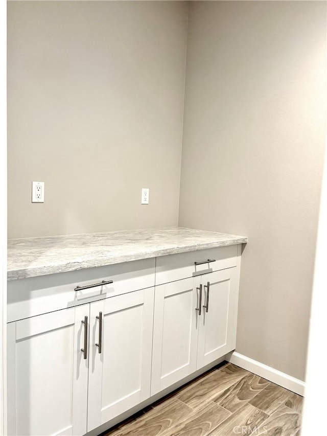 interior space featuring white cabinetry, light stone countertops, and light hardwood / wood-style flooring