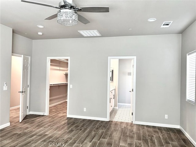 unfurnished bedroom featuring a closet, ceiling fan, dark hardwood / wood-style flooring, and a spacious closet