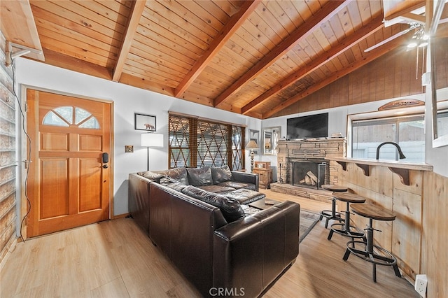 living room featuring a stone fireplace, wood ceiling, light hardwood / wood-style floors, and a healthy amount of sunlight