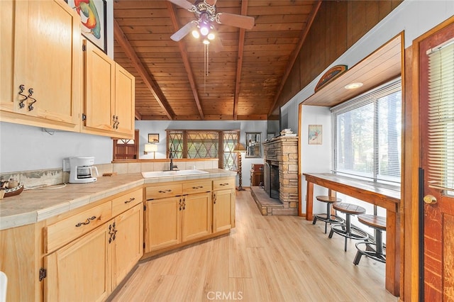 kitchen featuring lofted ceiling with beams, wood ceiling, sink, light hardwood / wood-style flooring, and tile countertops