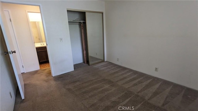 unfurnished bedroom featuring dark colored carpet and a closet