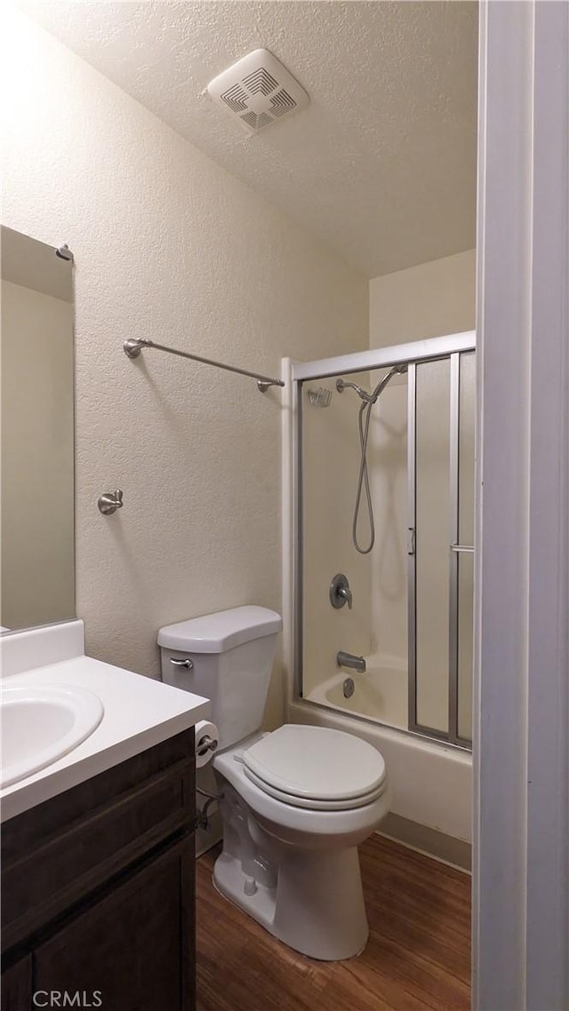 full bathroom featuring a textured ceiling, toilet, shower / bath combination with glass door, vanity, and hardwood / wood-style flooring