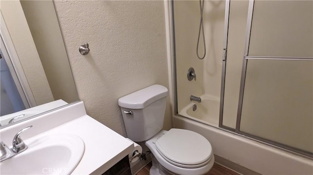 full bathroom featuring toilet, combined bath / shower with glass door, and vanity