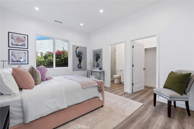 bedroom with light wood-type flooring, connected bathroom, a spacious closet, and a closet