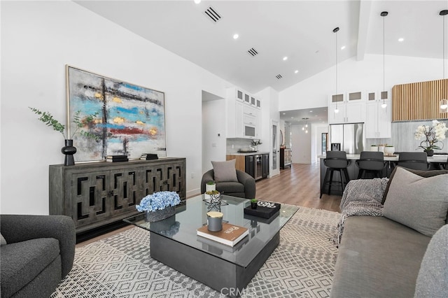 living room with beamed ceiling, hardwood / wood-style flooring, and high vaulted ceiling