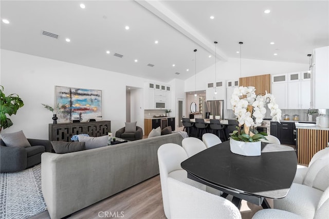 interior space featuring sink, beamed ceiling, light hardwood / wood-style floors, and high vaulted ceiling