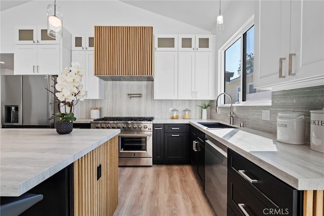 kitchen featuring stainless steel appliances, vaulted ceiling, sink, pendant lighting, and white cabinets