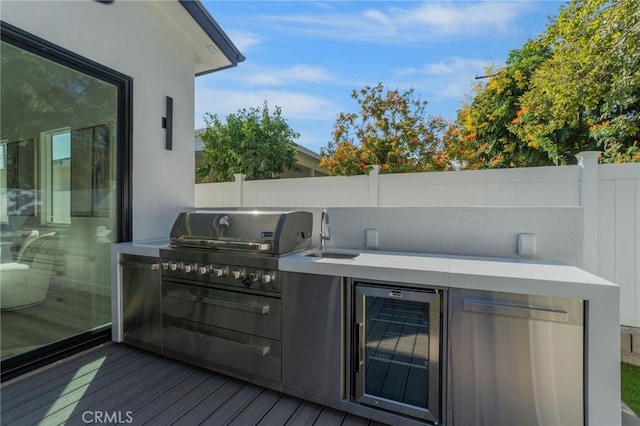 wooden terrace with an outdoor kitchen, wine cooler, grilling area, and sink