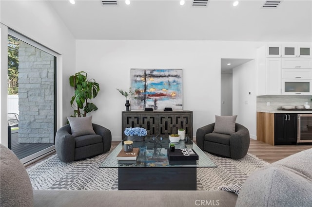 living room with a healthy amount of sunlight, light hardwood / wood-style floors, and beverage cooler