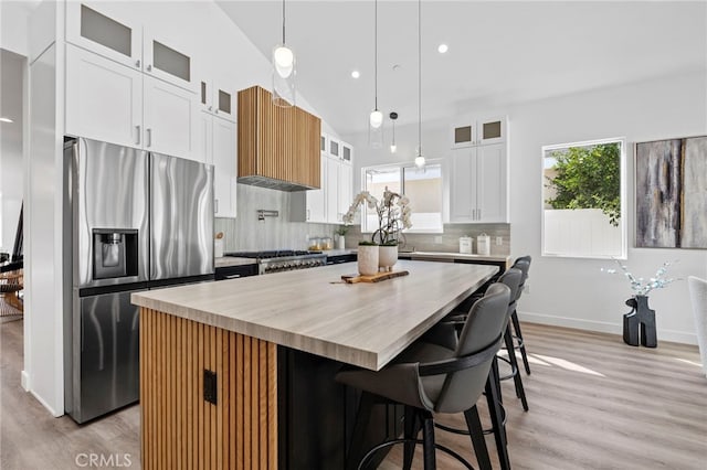 kitchen featuring custom range hood, stainless steel appliances, a center island, white cabinetry, and lofted ceiling