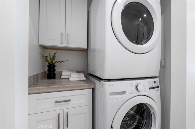 washroom featuring stacked washer and dryer and cabinets