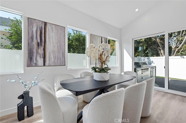 dining room featuring light wood-type flooring and vaulted ceiling