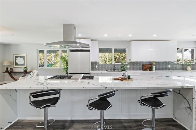 kitchen with a kitchen breakfast bar, light stone countertops, white cabinets, and extractor fan