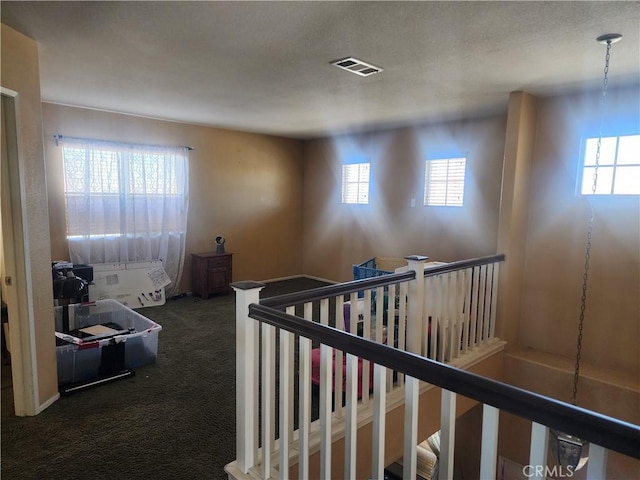 hallway featuring a healthy amount of sunlight and dark carpet