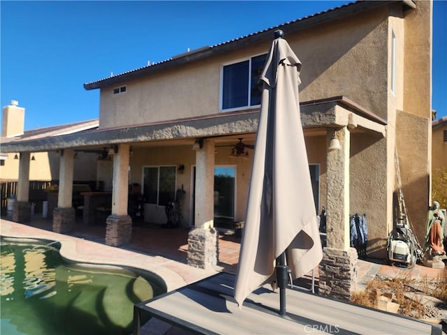 rear view of property featuring ceiling fan and a patio area