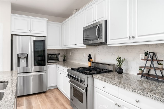 kitchen featuring light hardwood / wood-style flooring, white cabinetry, stainless steel appliances, and light stone counters