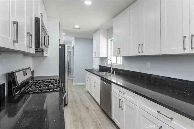10125 Sharp Ave, Arleta, CA 91331 - kitchen with a sink, appliances with stainless steel finishes, white cabinets, light wood-type flooring, and dark stone countertops