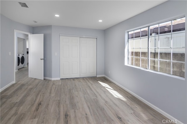 unfurnished bedroom featuring a closet, washer and dryer, and light wood-type flooring