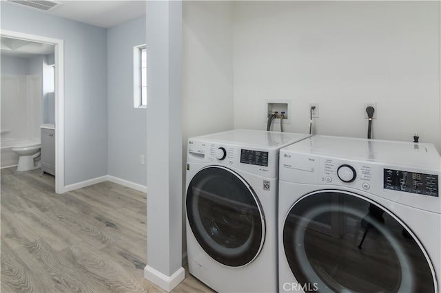 laundry area with independent washer and dryer and light hardwood / wood-style flooring