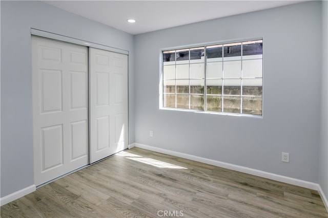 unfurnished bedroom with a closet and light hardwood / wood-style flooring