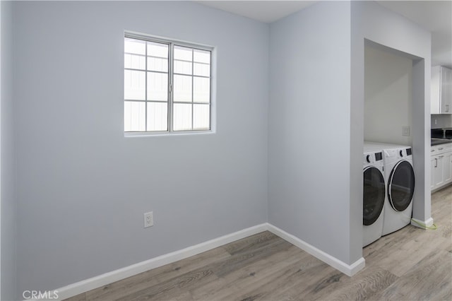 washroom featuring washer and clothes dryer, light hardwood / wood-style floors, and cabinets