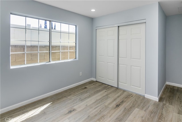 unfurnished bedroom with a closet and light hardwood / wood-style floors