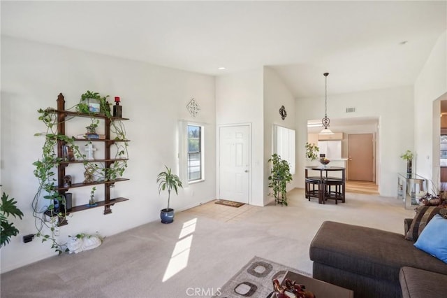 living area featuring a high ceiling, visible vents, and carpet floors