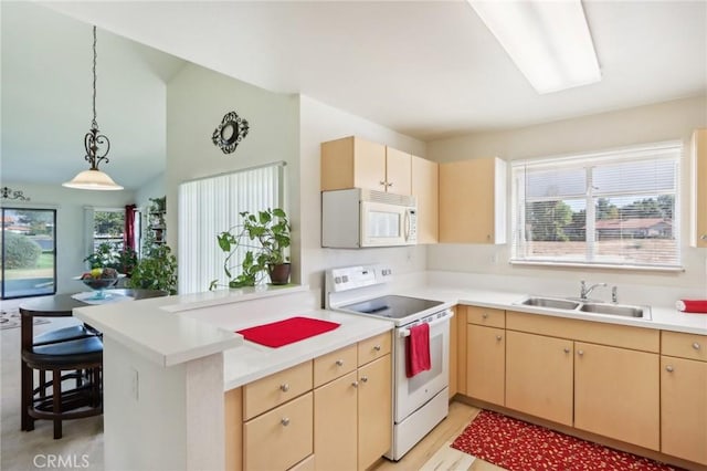 kitchen with decorative light fixtures, kitchen peninsula, sink, white appliances, and light brown cabinetry