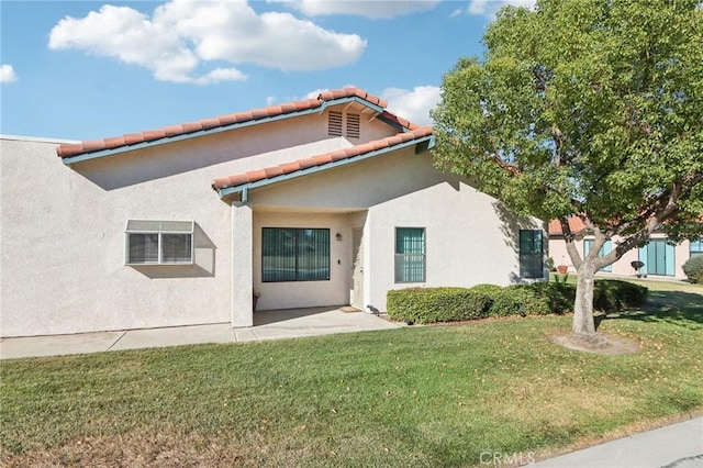 mediterranean / spanish-style house with a tiled roof, stucco siding, a patio, and a front lawn