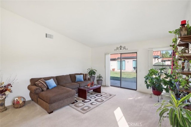 living area with vaulted ceiling, light colored carpet, and visible vents