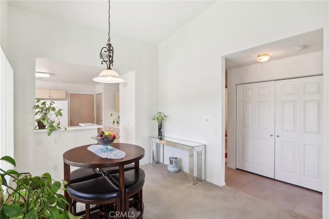 dining area featuring light carpet and vaulted ceiling