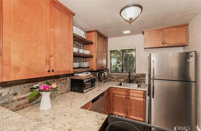 kitchen with light stone countertops, sink, backsplash, a textured ceiling, and appliances with stainless steel finishes