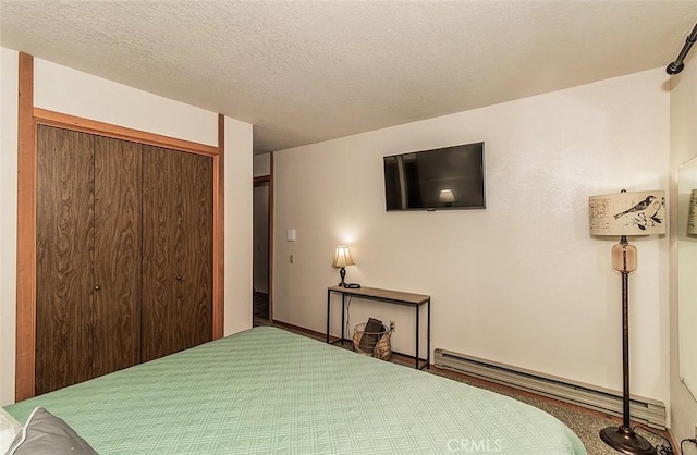 carpeted bedroom featuring a closet, a baseboard radiator, and a textured ceiling