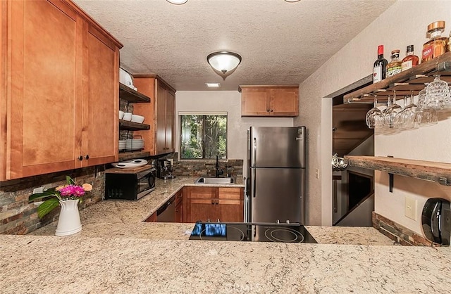 kitchen with a textured ceiling, backsplash, sink, and appliances with stainless steel finishes