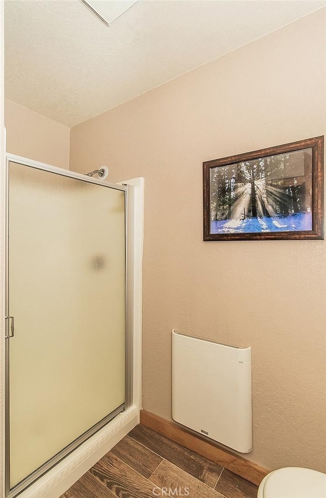 bathroom with hardwood / wood-style flooring, toilet, and an enclosed shower