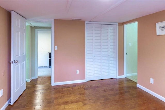 unfurnished bedroom with dark wood-type flooring and a closet