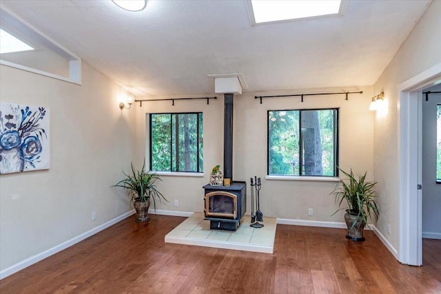 interior space with wood-type flooring, vaulted ceiling, and a wood stove