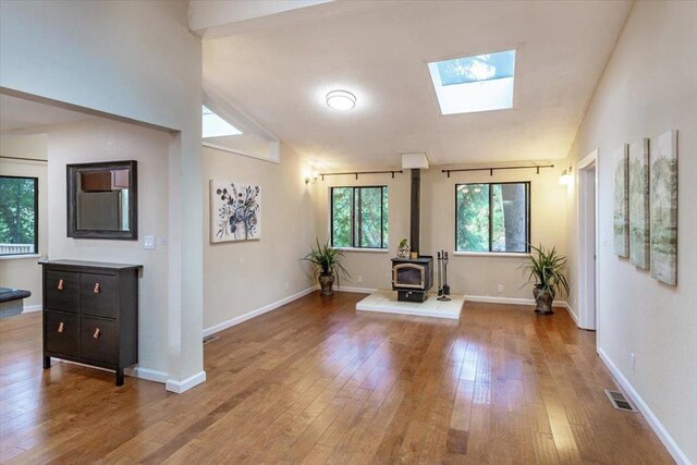 interior space featuring light hardwood / wood-style floors, a wood stove, and lofted ceiling with skylight