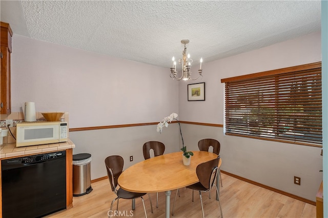 dining space with a textured ceiling, light hardwood / wood-style flooring, and a chandelier