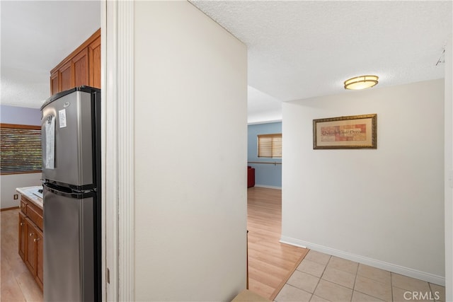 kitchen featuring a textured ceiling, stainless steel refrigerator, and light hardwood / wood-style flooring