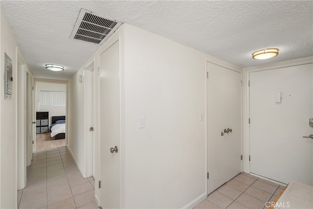 hallway featuring light tile patterned flooring and a textured ceiling