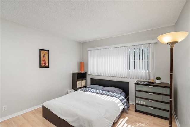 bedroom with light hardwood / wood-style floors and a textured ceiling