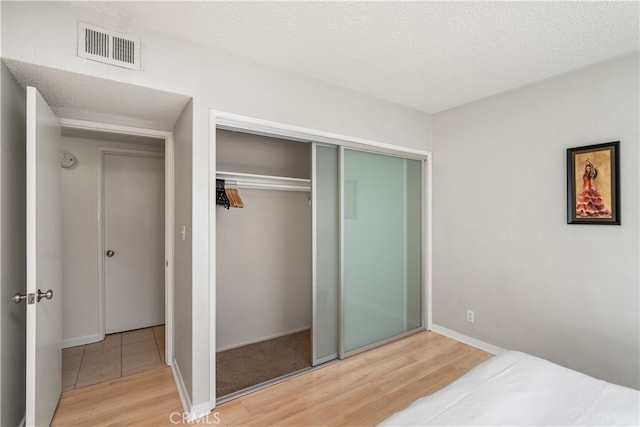 bedroom featuring hardwood / wood-style flooring, a closet, and a textured ceiling