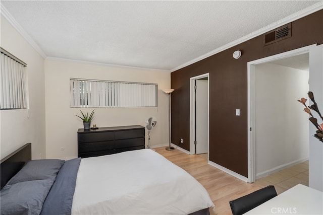 bedroom with crown molding, light hardwood / wood-style floors, and a textured ceiling