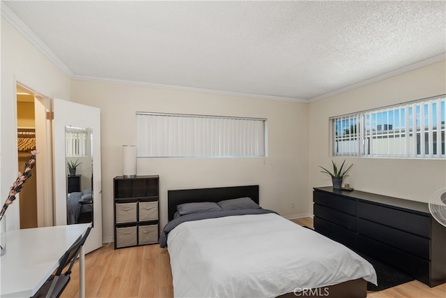 bedroom featuring a textured ceiling, light hardwood / wood-style flooring, and ornamental molding