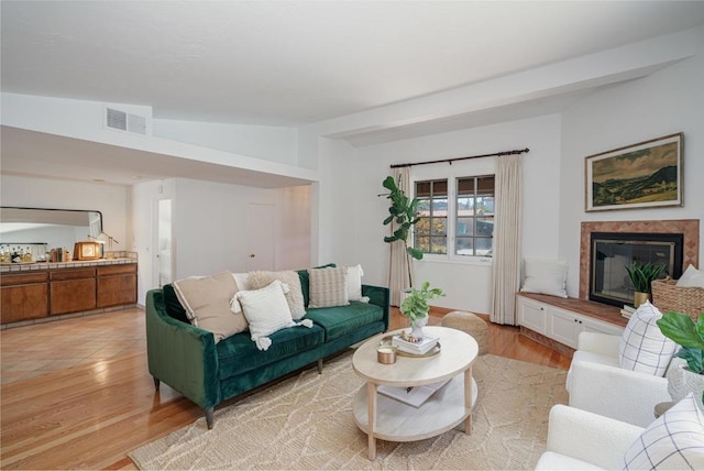 living room featuring vaulted ceiling, a premium fireplace, and light hardwood / wood-style floors